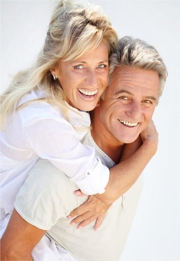 an elderly couple smiling with their dentures